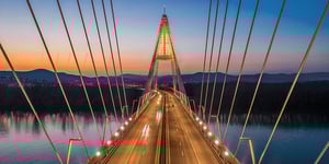 Unique bridge crossing river into beautiful sunset